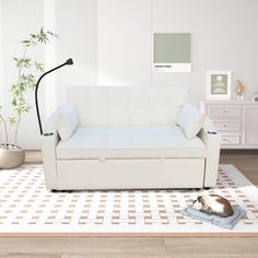 a white couch sitting on top of a rug in a living room next to a lamp