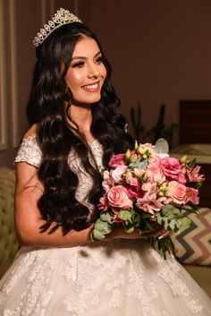 a woman wearing a tiara holding a bouquet of flowers and smiling at the camera