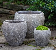 three cement planters sitting on top of a stone walkway