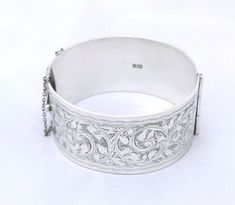 "Sterling silver cuff bangle, made from solid sheet silver - weight 70.6 gms.  This exceptionally wide and heavy bracelet is hallmarked Birmingham 1962. It measures 1.25\" wide, 31mm. One side has has stylized foliate hand engraving; the other side being plain, does show some small scratches from wear,, and one dark mark that could be buffed out by a silversmith/jeweller if desired." Silver Engraved Wide Band Bangle, Wide Band Sterling Silver Bracelet, Silver Wide Band Bangle For Formal Occasions, Formal Silver Bangle With Wide Band, Vintage Silver Solid Cuff Bracelet, Heavy Vintage Silver Cuff Bracelet, Vintage Silver Wide Band Cuff Bracelet, Vintage Wide Band Silver Cuff Bracelet, Silver Cuff Bangle