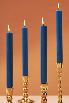 three blue candles are lined up next to each other on a table with gold accents