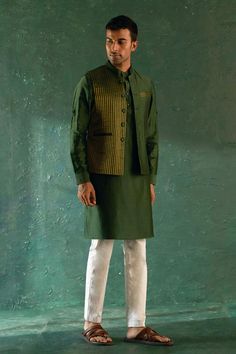 Deep green bundi with half stripe pattern. Paired with an inner kurta with pocket detailing and pant.
Components: 3
Pattern: Bundi: Stripe
Neckline: Mandarin Collar
Sleeve Type: Full Sleeves
Fabric: Kurta: Chanderi, Lining: Cotton, Pant: Poplin, Bundi: Chanderi and Silk Tissue
Color: Green
Other Details: 
Length:
Kurta: 41 inches
Pant: 40 inches
Bundi: 27 inches
Occasion: Sangeet - Aza Fashions Nehru Jackets, Full Sleeves, Deep Green, Mandarin Collar, Pocket Detail, Aza Fashion, Full Sleeve, Sleeve Type, Stripes Pattern