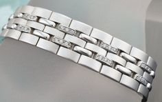 GENTS SIMULATED DIAMONDS BRACELET IN 14 KARAT WHITE GOLD DESIGN FOR JEWELRY SHOW. SKU-ART2 SETTING INFORMATION METAL ---------------14 KARAT WHITE GOLD SETTING -----------------PRONG SET FINISH------------HIGH POLISH AND SATIN FINISH WIDTH------------------------14 MM WEIGHT-47.5 GM SIMULATED DIAMONDS INFORMATION QUANTITY------------------------72 SHAPE-----------------------ROUND TOTAL WEIGHT----------------.75 CARAT CUSTOM ORDERS: Please feel free to contact us if you could not find the piece Modern White Diamond Bracelet For Formal Occasions, Luxury Diamond Bracelet For Anniversary, Silver Diamond Jubilee Bracelet In Platinum, Modern White Diamond Bracelet With Single Cut Diamonds, Modern Sterling Silver Bracelet With Diamonds, Modern White Gold Diamond Bracelet With Polished Finish, Modern White Gold Polished Diamond Bracelet, Modern Wedding Diamond Bracelet With Polished Finish, Silver Luxury Diamond Bracelet With Polished Finish