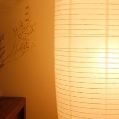 a lamp that is next to a table with a vase on it and a plant in the corner