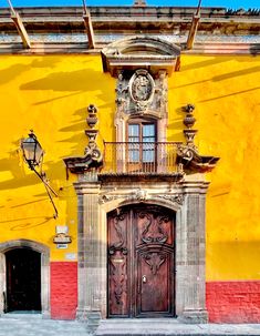 an old building with two doors and a clock on the front door is painted yellow