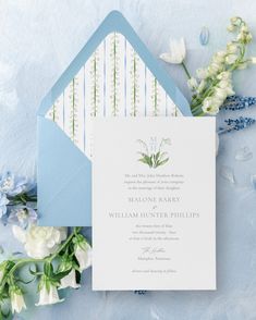 a blue and white wedding suite with flowers on the side, including a lettered envelope