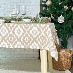 a table with a christmas tree in the background next to some baskets and wine glasses