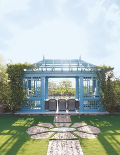 an outdoor area with grass and flowers on the ground, in front of a blue gazebo