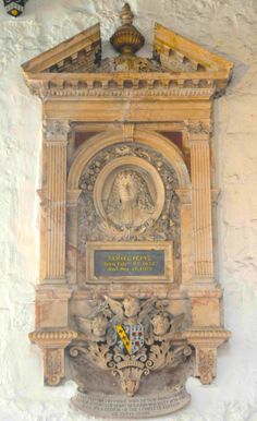 a clock mounted to the side of a wall with carvings on it's sides