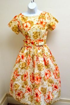 This is a cotton floral print dress that we recently obtained from an TX estate sale. The garment dates to the 1950s, and is a handmade garment. The fabric is a high quality cotton material with good weight. The print is floral, of peachy orange colored morning glory flowers, sage green leaves on an ivory/cream background. The sleeves are short cap sleeves. The bodice is fitted, and the skirt is full, but not a circle skirt. Photographed with a crinoline petticoat that is not included. The dress Retro Cotton Vintage Dress With Vintage Pattern, Cotton A-line Vintage Dress, Retro Cotton Dress With Vintage Pattern, 1950s Style Floral Print A-line Vintage Dress, 1950s Style A-line Vintage Dress With Floral Print, Retro Vintage Dress With Floral Print, 1950s Style Floral Print Vintage Dress, Vintage Cotton Dresses With Vintage Pattern, 1950s Short Sleeve Cotton Dress