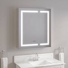 a bathroom with a sink, mirror and towel dispenser on the wall