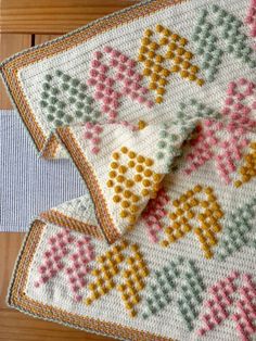 two crocheted placemats sitting next to each other on a wooden table