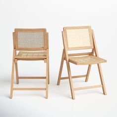 two wooden chairs sitting side by side on a white surface with one chair facing the other