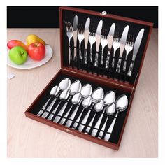 a wooden box filled with silverware next to apples and an apple on a plate