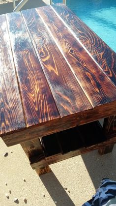 a wooden table sitting next to a swimming pool