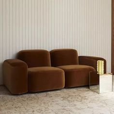 a brown couch sitting in front of a mirror on the floor next to a wall