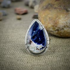 Embrace the calming beauty of our Sodalite ring, skillfully handcrafted with silver wire wrapping. This ring features a natural Sodalite gemstone, known for its deep blue hues and serene energy. Sized at 8, it's the perfect choice for those who appreciate unique and elegant, artisanal jewelry. The rich blue tones of the Sodalite paired with the sleek silver wire create a sophisticated piece that balances natural beauty with skilled craftsmanship. Ideal as a meaningful gift or a cherished persona Sodalite Ring, Boho Chic Design, Wire Wrapped Ring, Jewelry Elegant, Wire Wrapped Rings, Personalized Accessories, Blue Tones, Chic Design, Silver Wire