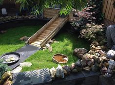 a garden with rocks, grass and a wooden slide in the middle of it's back yard