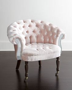 a pink and white chair sitting on top of a hard wood floor next to a wall