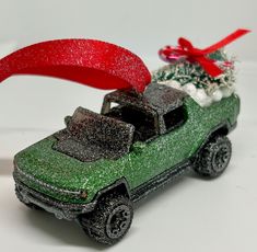 a green toy car with a christmas tree in the back and red ribbon on top