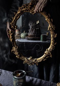 a person holding a mirror over a table with some food on it and a can of beer