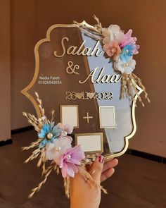 a person holding up a plaque with flowers on it