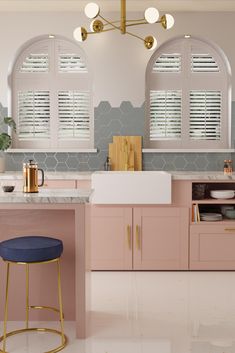 a pink kitchen with gold accents and marble counter tops is pictured in this image, there are two windows that have shutters on them