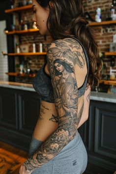 a woman with a tattoo on her arm and shoulder sitting in front of a bar