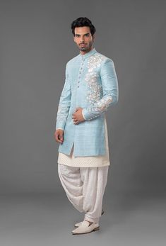 a man in a light blue sherwa with white pants and an embroidered jacket