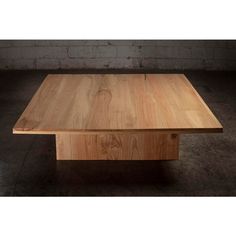 a wooden table sitting on top of a cement floor next to a brick wall in an empty room