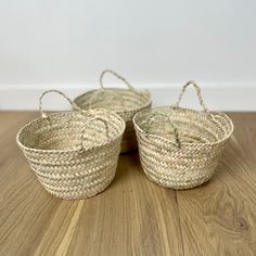 three woven baskets sitting on top of a wooden floor