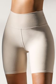 Close up front view of model from the waist down wearing the soft stretchy high-waisted sueded yuma Biker Short with a wide waistband Leggings With Built-in Shorts For Pilates, Compressive Shorts With Built-in Padding, Fitted Smoothing Short Length Tights, Fitted Smoothing Tights Short Length, High Stretch Shapewear With Built-in Shorts, Athleisure Fitted Leggings With Built-in Shorts, High Stretch Elastane Shorts, Solid Sculpting Shapewear In Short Length, Sculpting Solid Shapewear Short Length