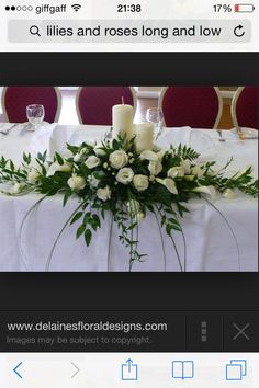 a table with white roses and candles on it for a wedding or special event decoration