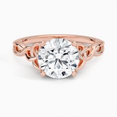 a rose gold engagement ring with a round diamond in the center and an intricate band around it