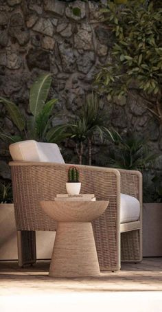 two chairs sitting next to each other in front of a stone wall and potted plants