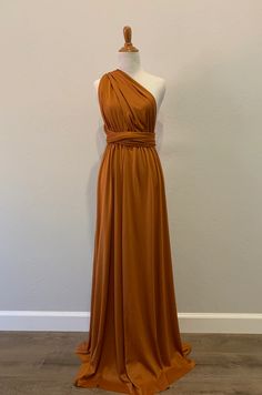 an orange dress on a mannequin with a white wall in the back ground