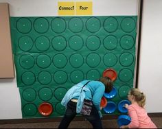 two children playing with frisbees in front of a wall that says connect four