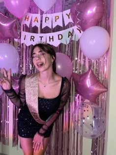 a woman standing in front of balloons and streamers with the words happy birthday on it