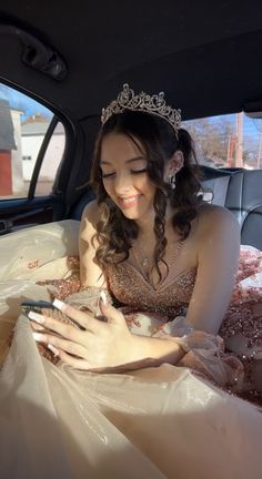 a woman wearing a tiara looking at her cell phone in the back seat of a car