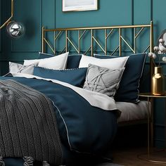 a bedroom with teal walls and gold headboard, blue comforter, grey bedding