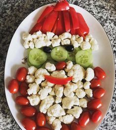 a white plate topped with cauliflower, cucumbers and tomatoes on top of it