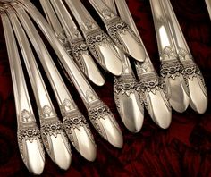 a group of silverware sitting on top of a red tablecloth covered table next to each other