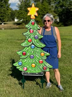 a woman standing next to a painted christmas tree