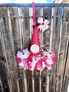 a red hat with white and pink flowers on it hanging from a wooden fence outside