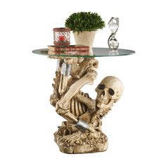 a table with a glass top and a skeleton sitting on it's side, next to a potted plant