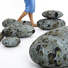 a person walking past some rocks with holes in it and one on the ground next to them