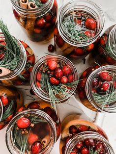 jars filled with cherries and rosemary sprigs