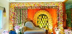 a decorated stage with flowers on the wall and a white couch in front of it