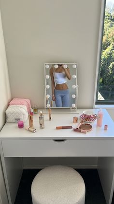 a woman taking a selfie in front of a vanity mirror with makeup on it