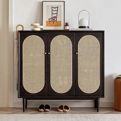 a black cabinet with two doors and some shoes on the floor in front of it